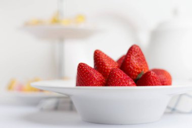 Kırsal beyaz arka planda seramik bir kasede taze çilek yığını