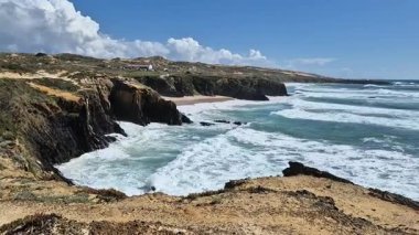 Atlantik Okyanusu 'nun güçlü gücü. Kayalık kıyı şeridinden koyu mavi suya ve büyük beyaz dalgalara kadar güneşli bir hava. Almograve, Portekiz 'deki Cabo Sardao' nun balıkçı patikasının bir parçası.