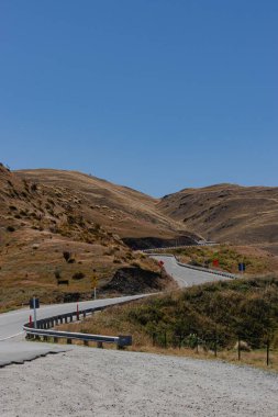 Berrak gökyüzünün altında dönen dağ yolu