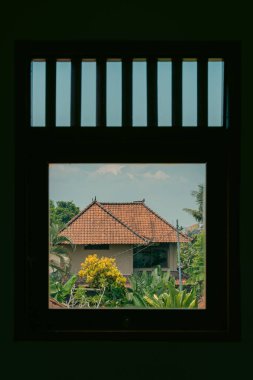 Çevresi yeşilliklerle çevrili, pencere çerçeveli geleneksel bir ev