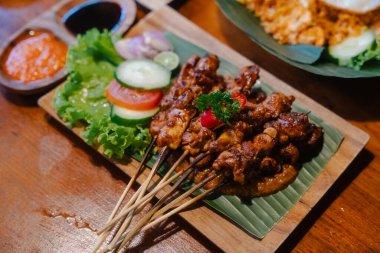 Skewered grilled chicken satay served with fresh vegetables and  clipart