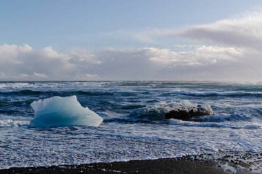 Arktik deniz manzarası. Önünde büyük bir buzdağı ve dalgalar var.