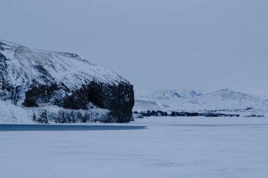 Donmuş bir gölün kenarındaki karlı uçurum