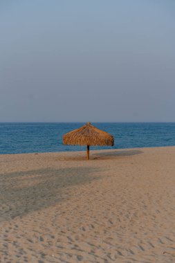 Kumlu bir sahilde saman şemsiyesi