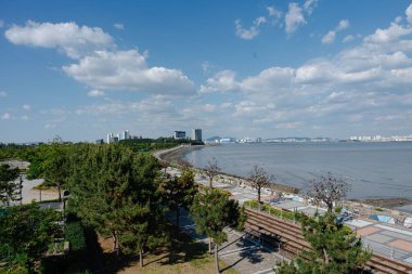 Mavi gökyüzü ve uzak binalarla kıyı kenti