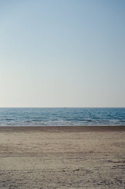 Sakin okyanus dalgalarıyla minimalist kumlu sahil