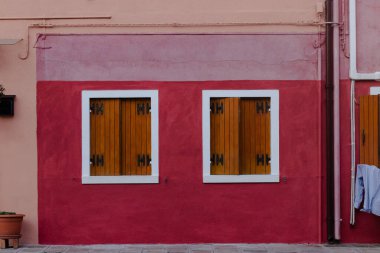 Ahşap panjurlu canlı kırmızı ve pembe bina cephesi