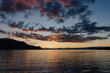 Sakin suların ve dağların üzerinde alacakaranlık.