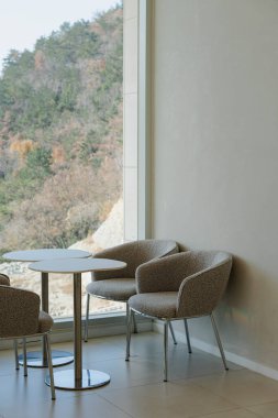 Dağ manzaralı pencere kenarındaki modern sandalyeler ve masa.
