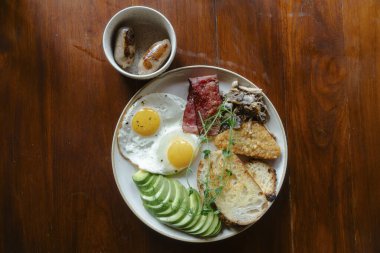 Yumurtalı, pastırmalı ve tostlu bir kahvaltı tabağı.
