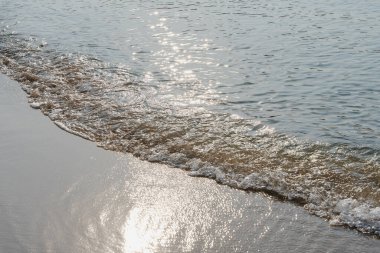 Yumuşak dalgalar kumlu bir kıyıya vuruyor.