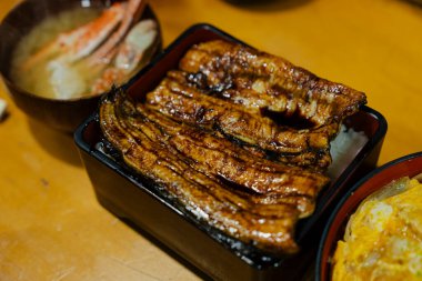 Bir kutuda pilavın üstünde ızgara yılan balığı.