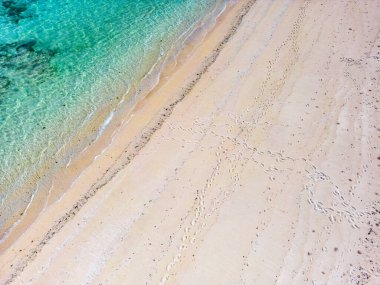 Gili Adası, Gili Meno 'daki ayak izleriyle güzel tropikal okyanus ve kumlu sahil manzarası. Lombok, Bali, Endonezya' da insansız hava aracı tarafından havadan manzara. 