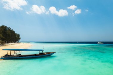 Turkuaz okyanuslu tropik kumlu sahil ve Endonezya 'nın Lombok kentindeki Gili adalarından biri olan Gili Meno' da tekneler.