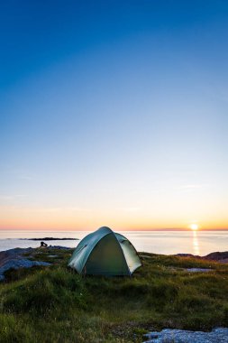 Norveç 'te, Andoya, Nordland, Norveç' te gece yarısı güneşi ve deniziyle çadırda kamp yapmak.