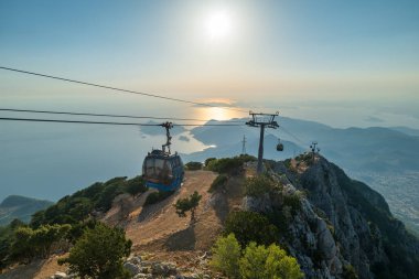 Türkiye 'nin Fethiye ilçesindeki Oludeniz plajına bakan teleferikle gün batımında Babadag dağ manzarası