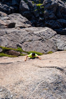 Genç adam kayalara tırmanıyor, kayalara tırmanıyor, kayalara tırmanıyor.