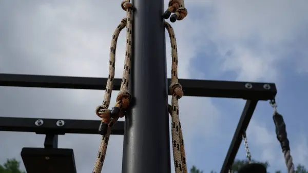 Açık hava fitness ekipmanlarına yakın çekim: Çekme için düğümlü halatlar ve açık hava fitness ekipmanlarına yakından bakmak, barfiks çekmek ve tırmanma egzersizleri için tasarlanmış halatları göstermek. Düğümlü bu ipler çok yönlü seçenekler sağlar