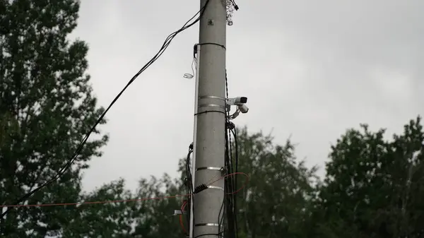 İki Gözetleme Kameralı Güç Kutbu iki güvenlik kameralı bir elektrik direğini gösteriyor. Kameralar kutbun tepesine monte edilmiş ve farklı yönlere yöneltilerek bölgenin kapsamlı bir şekilde görüntülenmesi sağlanıyor. Bu resim hasta.
