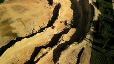 Dolomite Açık Çukur Mayını 'nın, Ormanın Yanındaki Çalışan Kamyon ve Kazıcılarla Hava Görüntüsü İnsansız Hava Aracı görüntüsü aktif kamyonları ve kazıcıları olan açık bir dolomit madeni gösteriyor. Madencilik ekipmanları çıkarma ve tran ile meşgul.