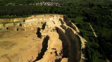 Arkaplanda Çalışan Kamyon ve Residential Area ile Açık Çukur Dolomit Ocağı ağır kamyonların hareket halinde görüldüğü, kumlu arazide malzeme taşıdığı açık çukur dolomit ocağının büyüleyici hava görüntüsü. Taş ocağı kuşatılmıştır.