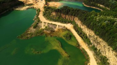 Sandy Trails ve Görünür Uçurumlar ile İki Orman Gölünün Hava Manzarası Bu hava aracı, sık bir ormanın ortasında yer alan iki dingin gölü gösteriyor. Sandy göllerin etrafında dolanıp doğal ortamı güzelleştiriyor. Belirgin cli