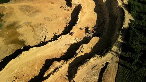 Dolomite Açık Çukur Mayını 'nın, Ormanın Yanındaki Çalışan Kamyon ve Kazıcılarla Hava Görüntüsü İnsansız Hava Aracı görüntüsü aktif kamyonları ve kazıcıları olan açık bir dolomit madeni gösteriyor. Madencilik ekipmanları çıkarma ve tran ile meşgul.