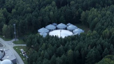 Distant Aerial View of Dome Cluster in Nature A distant aerial view showcasing a futuristic cluster of domes nestled in a natural setting. The unique combination of modern design and the surrounding forest creates a stunning visual contrast, highligh clipart