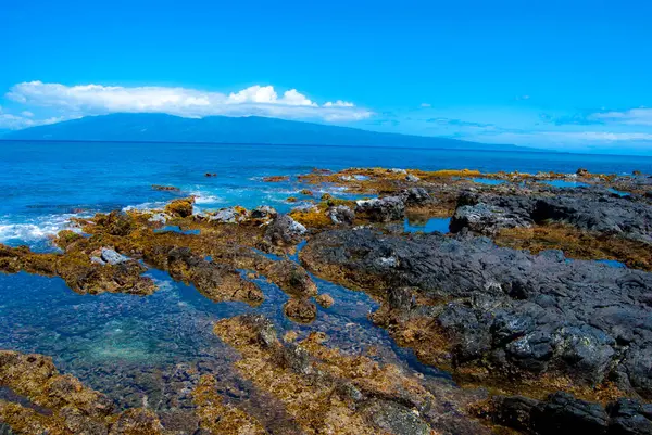 Rocky Tidepools on the Coast of Maui, Hawaii with an Island and Clouds in the Distance