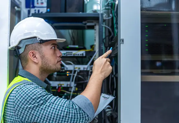 İnternet kablosu ve sunucuları üzerinde çalışan bir IT teknisyeni ve kağıt üzerinde listeyi kontrol etmeye çalışıyor