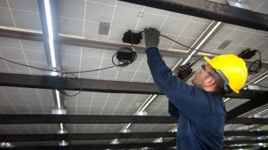 Mühendislik teknik servisi güneş panelini kontrol ederken aynı zamanda güneş paneli çalışmalarını kontrol etmek için iş arkadaşlarıyla iletişim kurmak için telsiz kullanıyor.