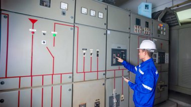 Elektrik mühendisleri ana elektrik kontrol panelleri ve anahtarlar, tabletlerdeki kayıt değerleri, elektrikçi fabrikadaki elektrik sistemlerini kontrol eder.