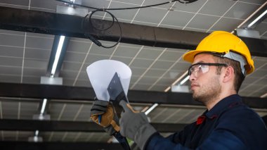 Mühendis teknik servisi, kurulum güneş pili panelini kontrol ediyor ve panodaki tüm listeleri ve güneş paneline düzgün bağlanan kabloları kontrol ediyor.