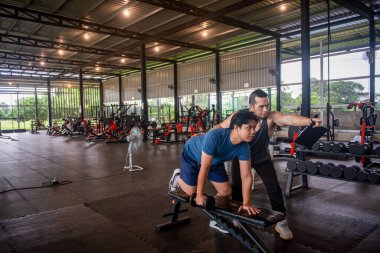 Erkek antrenör, spor salonundaki hizmetleri kullanmaya gelen müşterilere doğru egzersiz duruşlarını öğretiyor..