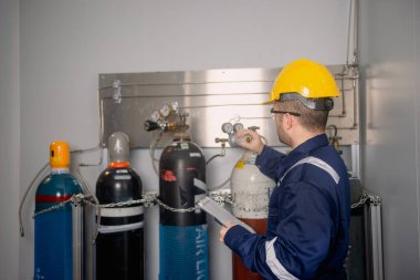 Mühendisler, sanayi tesisindeki gaz miktarını kontrol etmek için gaz tanklarının hacmini ve basınç vanalarını kontrol ediyor..