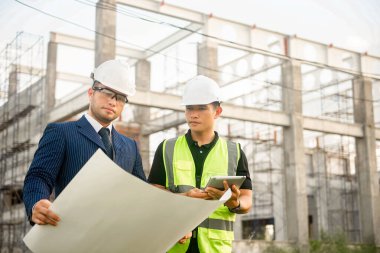 Mühendis ve mimar inşaat planının ilerlemesini izliyor ve bunların doğruluğunu doğruluyor..