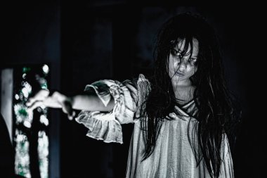 Yüzü nefret ve korkuyla dolu kadın hayalet perili bir odada beyaz bir elbise giyiyor.