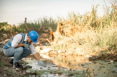 Su kaynakları mühendisleri çöplerle dolu bir toplumda bir kanalın kalitesini inceler..