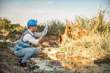 Su kaynakları mühendisleri çöplerle dolu bir toplumda bir kanalın kalitesini inceler..