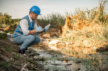 Su kaynakları mühendisleri çöplerle dolu bir toplumda bir kanalın kalitesini inceler..