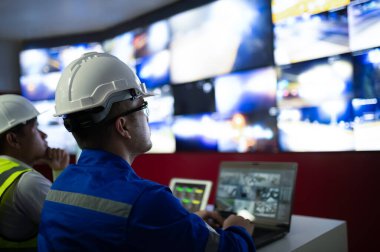 İki CCTV memuru bölgedeki trafiği kontrol odasındaki birden fazla monitörden izliyor..