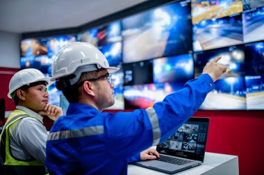 İki CCTV memuru bölgedeki trafiği kontrol odasındaki birden fazla monitörden izliyor..