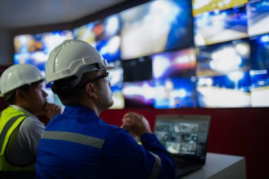 İki CCTV memuru bölgedeki trafiği kontrol odasındaki birden fazla monitörden izliyor..