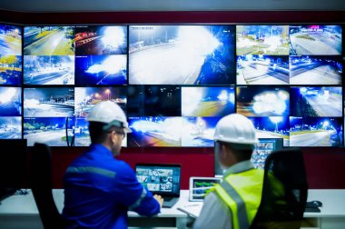 İki CCTV memuru bölgedeki trafiği kontrol odasındaki birden fazla monitörden izliyor..