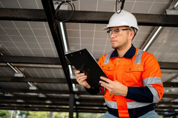 Erkek bakım mühendisi güneş panellerinin çalışmasını denetliyor ve tamirat yapıyor..