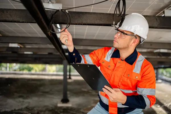 Erkek bakım mühendisi güneş panellerinin çalışmasını denetliyor ve tamirat yapıyor..