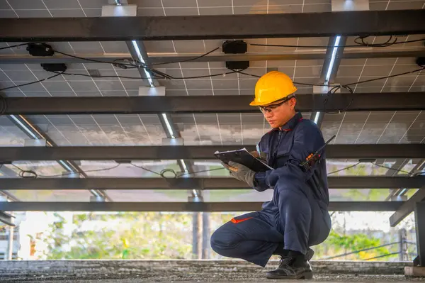 Güneş paneli kurucusu güneş panellerinin bakımını kontrol ediyor ve bir panoya not alıyor.