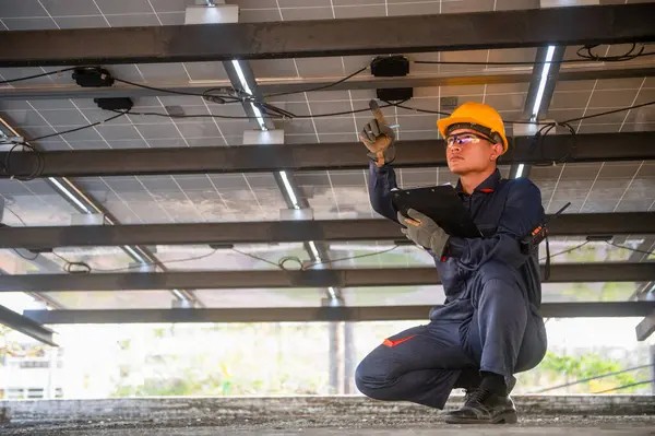 Bir güneş paneli kurucusu parmağını arızalı bir elektrik hattına doğrultuyor ve bunu bir panoya not ediyor..