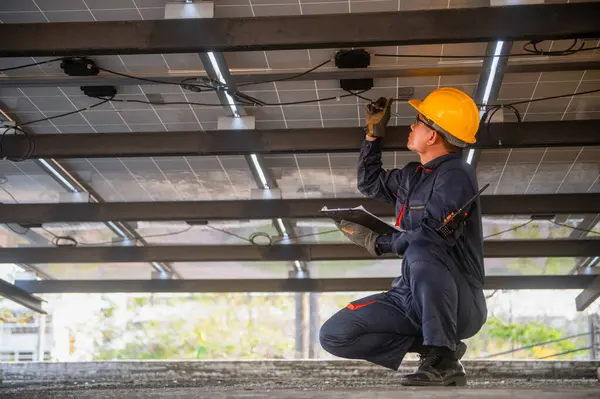Güneş paneli kurucusu güneş panellerinin bakımını kontrol ediyor ve bir panoya not alıyor.