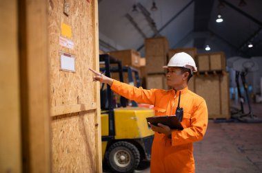 Bir memur depodaki bir panoda mal ve kayıt detaylarını kontrol ediyor..